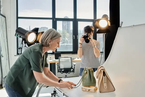 Жінка середнього віку фотографує сумки в професійній фотостудії. — стокове фото