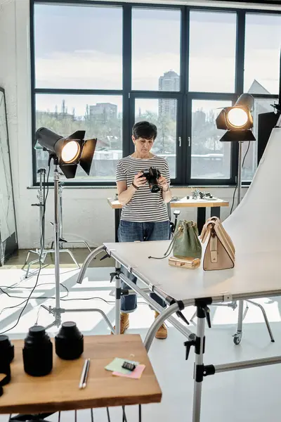 A middle-aged photographer confidently stands with camera in a studio, taking shot of bags — Stock Photo