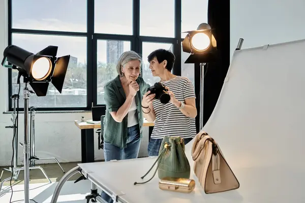 A middle-aged woman taking a picture of bags in a professional photo studio setup. — Stock Photo