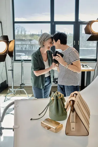 A middle-aged women capturing photos of bags at a modern photo studio. — Stock Photo