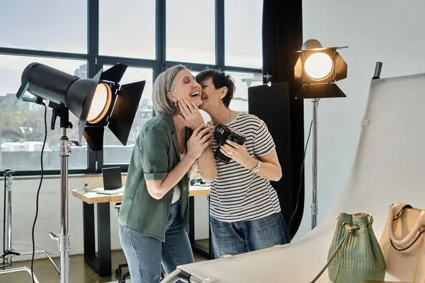 A middle-aged woman passionately kisses partner in front of a camera in a professional photo studio. — Stock Photo