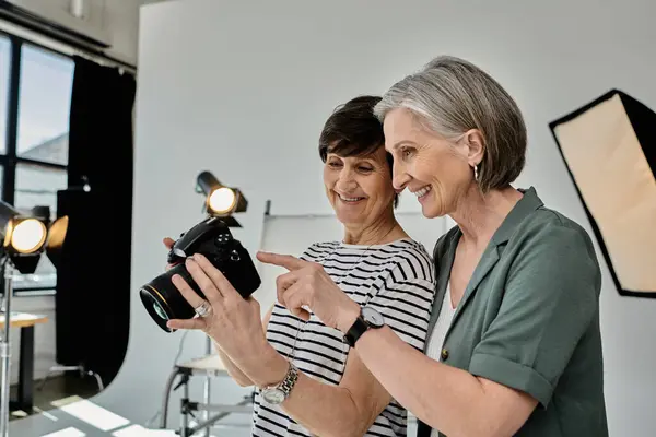 Zwei Frauen mittleren Alters halten einen Moment mit der Kamera in einem professionellen Fotostudio fest. — Stockfoto
