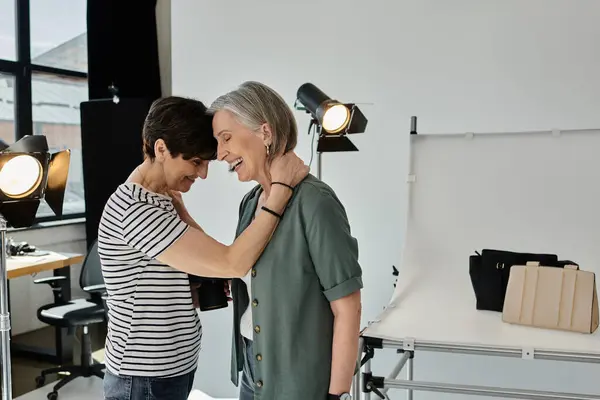 A middle-aged lesbian couple stands confidently in a modern photo studio, posing in front of a camera. — Stock Photo