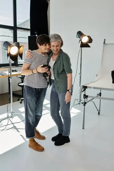 A middle aged lesbian couple standing together in a bright, professional photo studio, working on a project. — Stock Photo