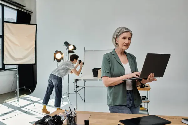 Woman with short hair stands at laptop in sleek office, collaborating on project. — Stock Photo