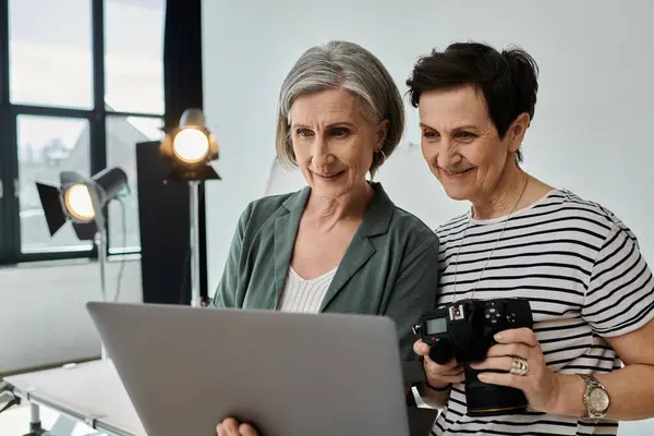 Middle-aged women attentively work together on a laptop in a modern photo studio. — Stock Photo