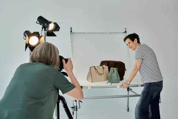 Photographer snaps a shot of a woman posing in front of a bags in a modern photo studio. — Stock Photo