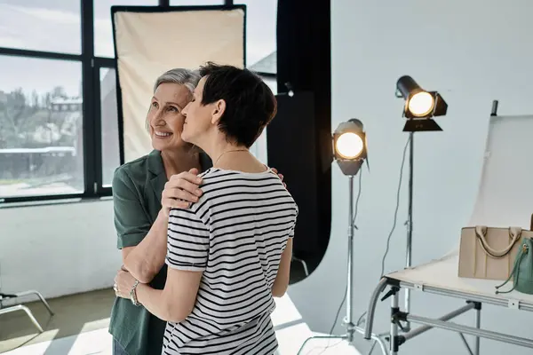 Two middle aged women confidently stand side by side in a professional modern studio setting. — Stock Photo