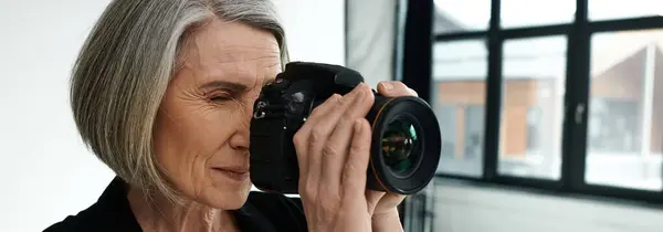 Middle-aged woman in a photo studio taking a picture with a camera. — Stock Photo