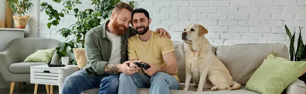 Barbuto gay coppia assorto in video gioco con loro leale labrador su il divano. — Foto stock