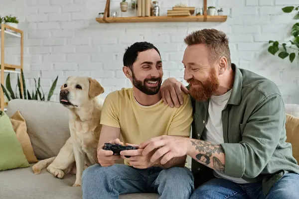 Гей-пара і їх собака насолоджуються якісним часом, граючи в відеогру на дивані. — стокове фото
