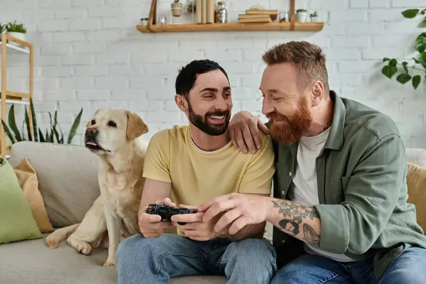 Gay coppia e loro cane godere di qualità tempo giocare video gioco su il divano. — Foto stock