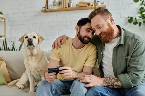 Двоє чоловіків, захоплених у відеогрі, сидять на дивані у своїй вітальні зі своїм собакою поруч. — стокове фото