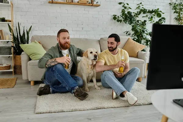 Два чоловіки з собакою спостерігають за спортом на дивані в затишній вітальні разом. — стокове фото