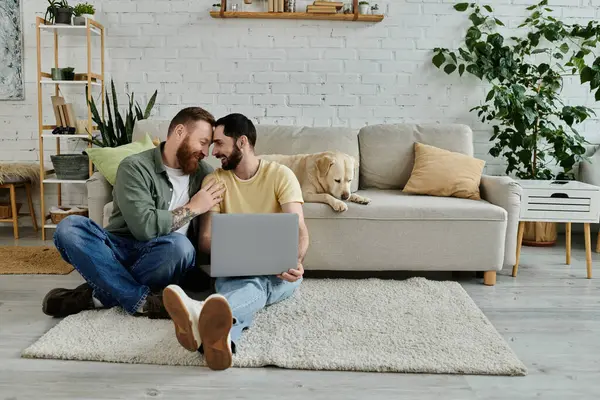 Bärtiges schwules Paar arbeitet mit Laptop auf dem Fußboden, begleitet von seinem treuen Labrador-Hund. — Stockfoto