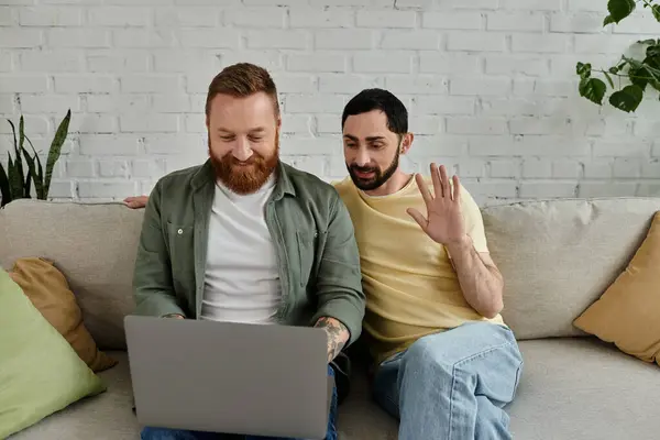 Bearded gay couple on couch, intently focused on laptop screen in cozy living room setting. — Stock Photo
