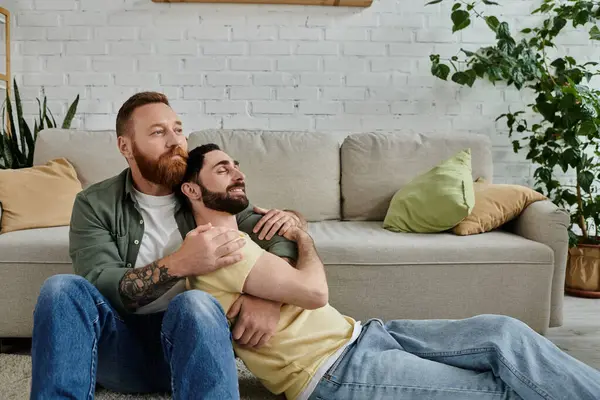 Two bearded men relax on a couch, enjoying each others company in a warm living room. — Stock Photo