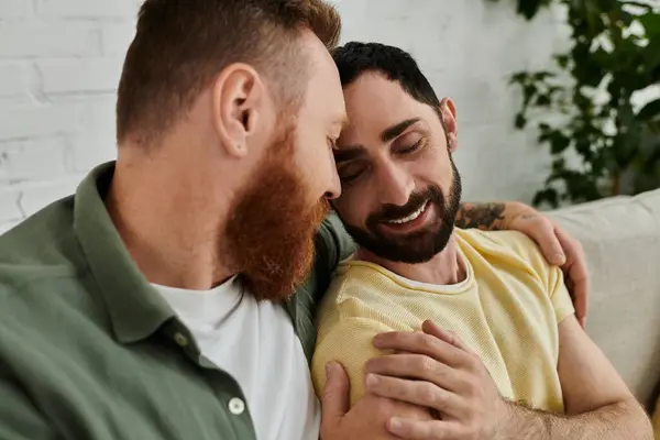 Bearded gay couple relax together on sofa, enjoying quality time in stylishly decorated living room. — Stock Photo