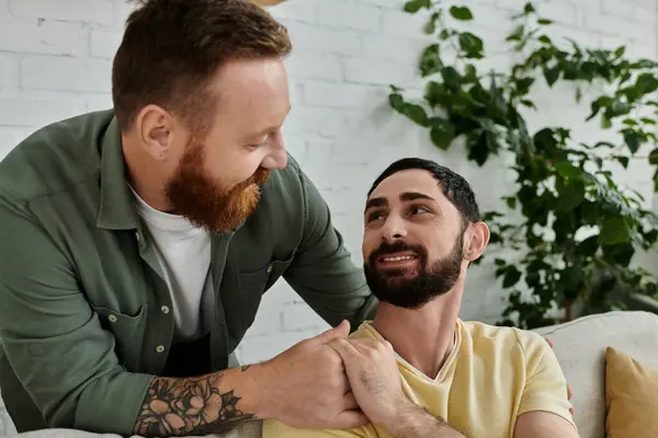 Homme barbu sourit chaudement à son partenaire dans le salon confortable — Photo de stock