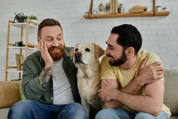 Un homme barbu et son partenaire profitent d'un moment de calme assis sur un canapé avec leur labrador fidèle dans le salon. — Photo de stock