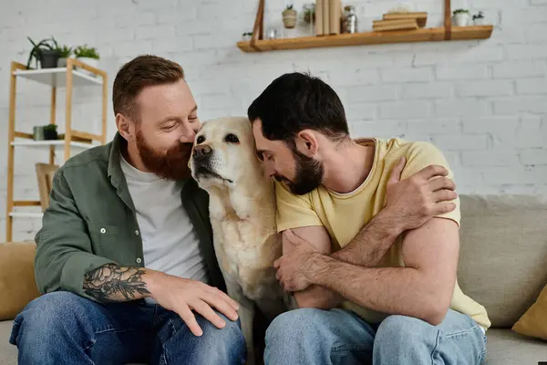 Dois homens, um com barba, sentam-se em um sofá aconchegante com seu labrador em uma sala de estar quente e convidativa. — Fotografia de Stock