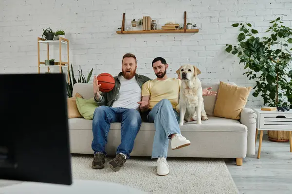 Two stylish men, one bearded, unwind on a cozy couch with their labrador in a classy living room setting. — Stock Photo