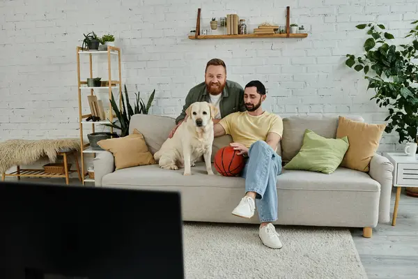Two men with beards relax on a couch with their Labrador in a cozy living room setting. — Stock Photo