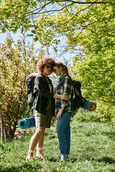 A young lesbian couple with backpacks hikes through the woods, enjoying a day outdoors. — Stock Photo