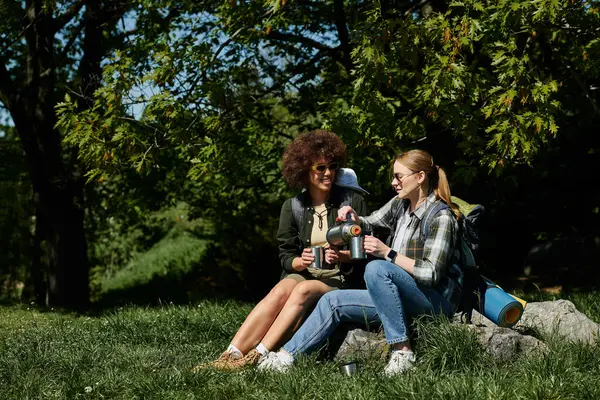 Duas jovens mulheres, um casal lésbico, desfrutam de uma pausa para o café durante sua caminhada na natureza. — Fotografia de Stock