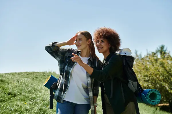Due giovani donne, una con i capelli ricci e l'altra con i capelli lisci, stanno facendo escursioni nel deserto. — Foto stock