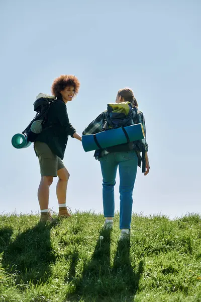 Una giovane coppia lesbica multiculturale cammina insieme in una giornata di sole, godendo del tempo all'aria aperta nella natura selvaggia. — Stock Photo