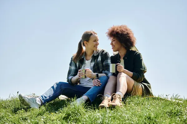 A young lesbian couple enjoys a cup of coffee on a scenic hike in the wilderness. — Stock Photo