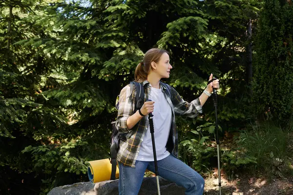 A young woman hikes through a lush forest on a sunny summer day, enjoying the outdoors. — Stock Photo