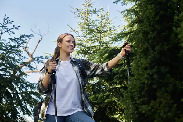 A young blonde woman hikes through a forest on a sunny summer day. — Stock Photo