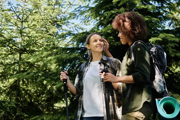 Two young women, a lesbian couple, hike through a forest together, enjoying the outdoors. — Stock Photo