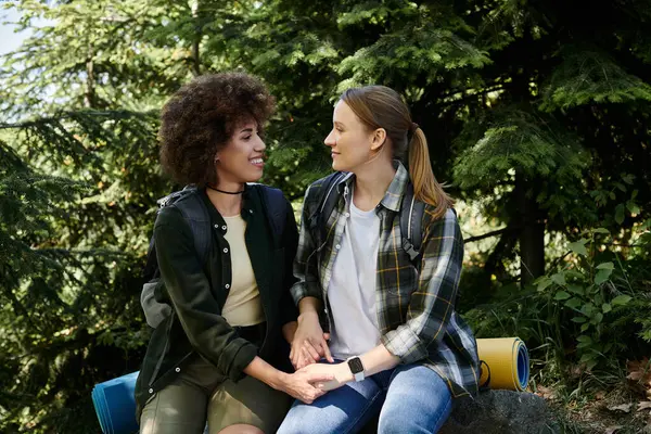 A young lesbian couple enjoys a hike through the woods, taking a break to rest and share a moment of intimacy. — Stock Photo