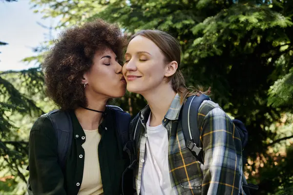Ein junges lesbisches Paar genießt eine Wanderung im Wald und teilt einen zärtlichen Moment. — Stockfoto