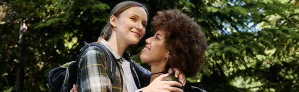 A young lesbian couple hikes together in a forest, sharing a moment of love and connection in nature. — Stock Photo