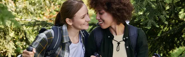 A young lesbian couple hikes through a lush forest, enjoying each others company. — Stock Photo