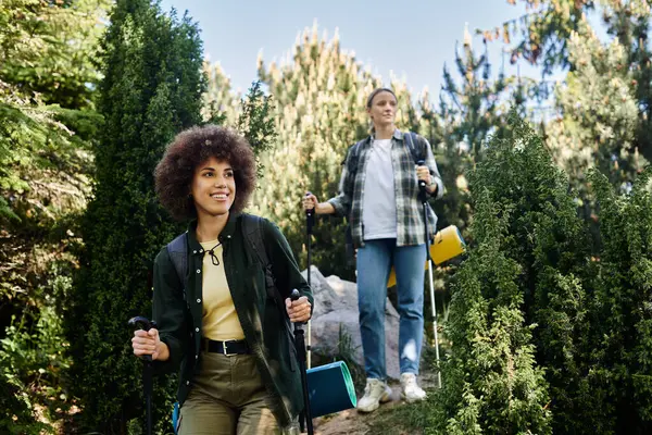 Two young women hike through the woods together, enjoying the outdoors and each others company. — Stock Photo