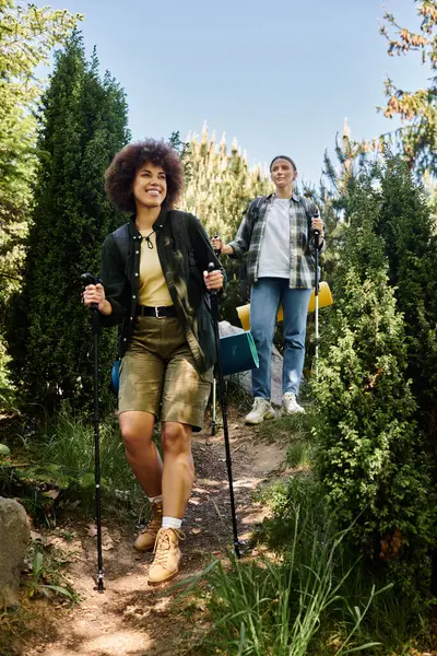 A young lesbian couple hikes through the woods together, smiling and enjoying the outdoors. — Stock Photo