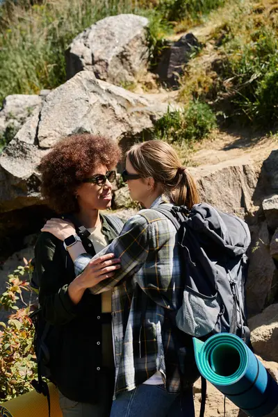 A young lesbian couple embraces while hiking, enjoying a beautiful outdoor experience in the wilderness. — Stock Photo