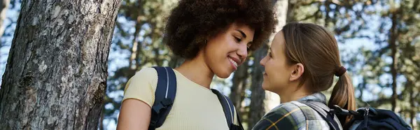Two young women, a lesbian couple, hike together in a forest, enjoying the beauty of nature. — Stock Photo