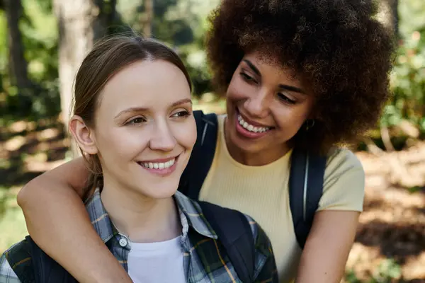 A young lesbian couple, one with afro hair, enjoys a hike in the forest together. — Stock Photo
