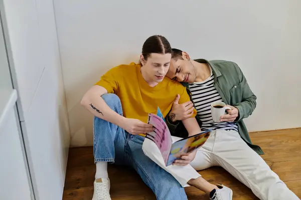 Um jovem casal gay relaxa em seu apartamento moderno, lendo uma revista e desfrutando de café. — Fotografia de Stock