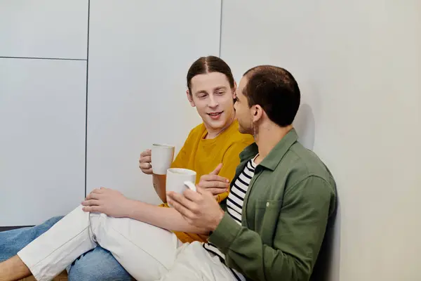 A young gay couple relaxes and enjoys coffee together in a modern apartment. — Stock Photo