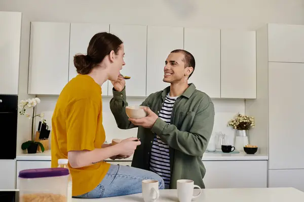 A young gay couple enjoys a light breakfast together in their modern apartment kitchen. — Stock Photo