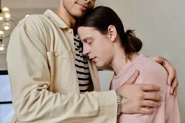 Ein junges schwules Paar umarmt sich in einer modernen Wohnung und zeigt einen zarten Moment der Intimität und Zuneigung. — Stockfoto