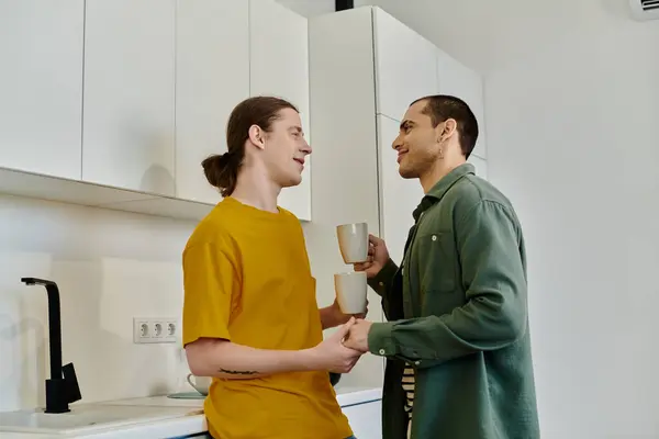 Молодая гей-пара вместе пьет кофе на кухне своей современной квартиры. — стоковое фото