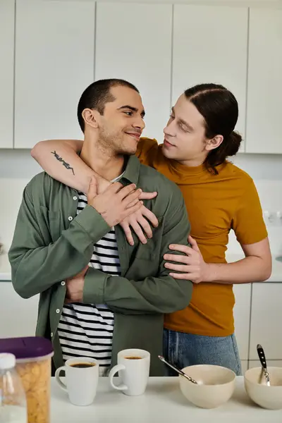 A young gay couple embraces in their modern kitchen, showcasing their love and intimacy. — Stock Photo